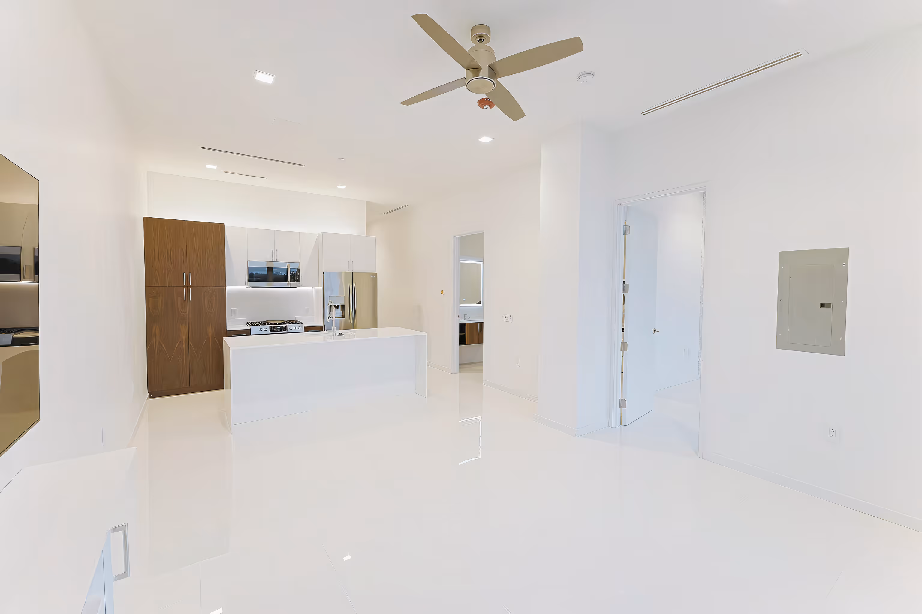 Modern kitchen with white floors, white island, stainless steel appliances, wooden cabinets, and a ceiling fan.