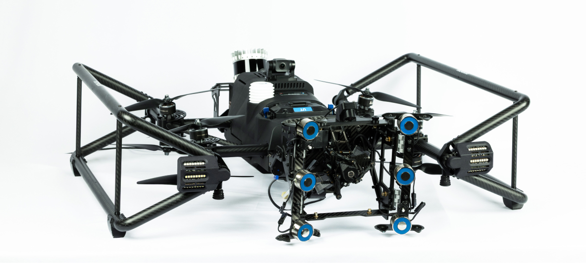 Front view of a black quadcopter drone with carbon fiber frame, multiple propellers, and a camera mounted on top.
