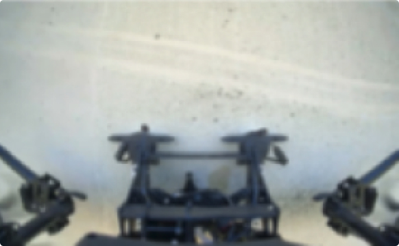 Blurry top-down view of a mechanical or robotic structure with gears and arms.