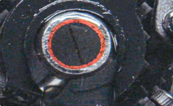 Close-up of a mechanical component with a circular part featuring a red ring and metallic details.