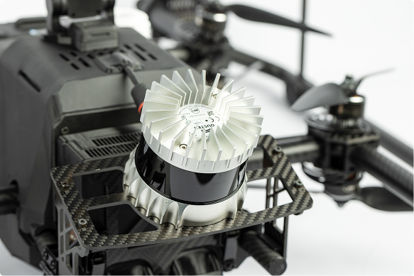 Close-up of a LiDAR component with a silver fan-like heat sink and carbon fiber frame parts.