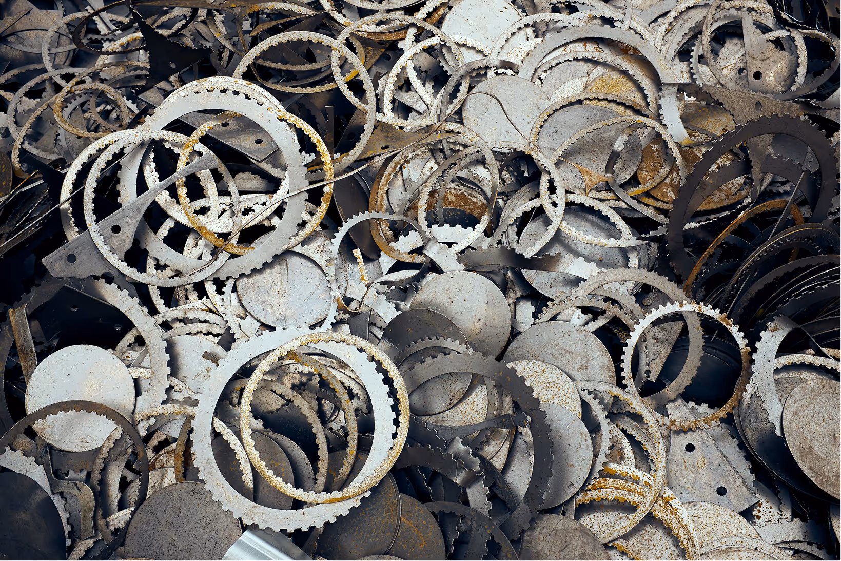 Pile of various rusty, circular metal gears and rings overlapping each other.
