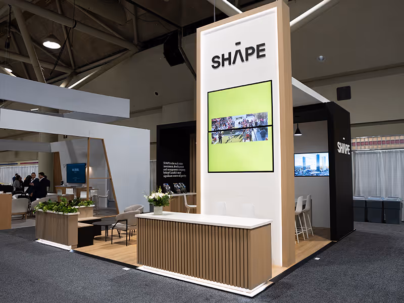 custom 20x20 trade show booth with a custom counter, media column, and lounge seating space