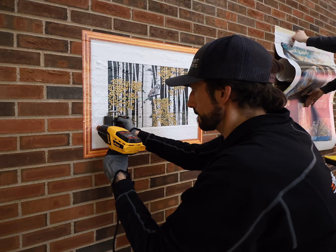graphic technician applying an artwork vinyl decal to a brick wall