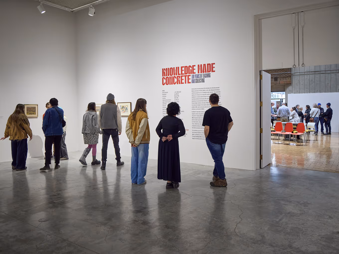 group in an art gallery reading the wall graphics text for an exhibition in calgary