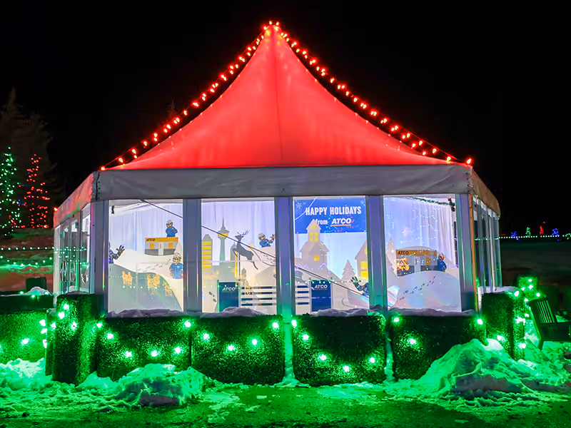 tent with an enclosed ATCO Christmas display at night featuring colourful lights.