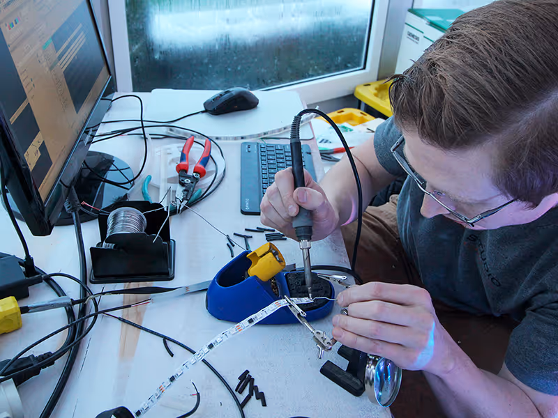 Calgary installer sodering LED light strips for a custom Christmas display at Spruce Meadows.