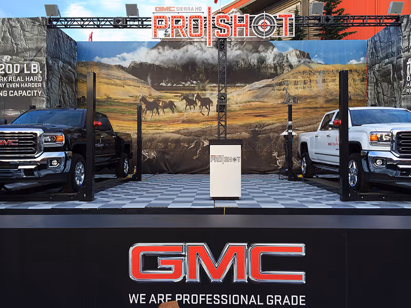 GMC ProShot setup featuring two Sierra HD trucks on elevated platforms in a fully branded midway environment.