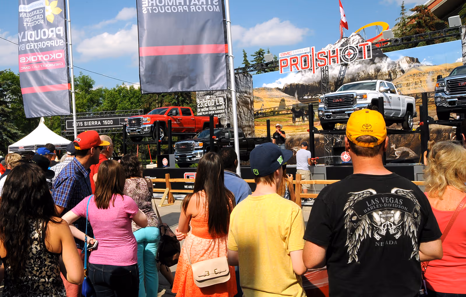 Crowd watches the GMC ProShot experiential activation with multiple Sierra HD trucks displayed on raised platforms.