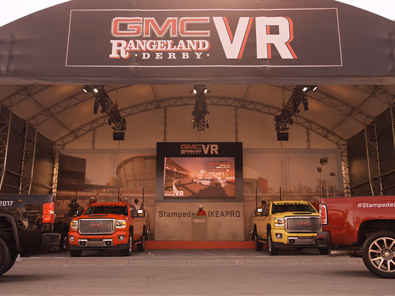GMC Rangeland Derby VR stage with red and yellow Sierra trucks flanking a central racing screen.