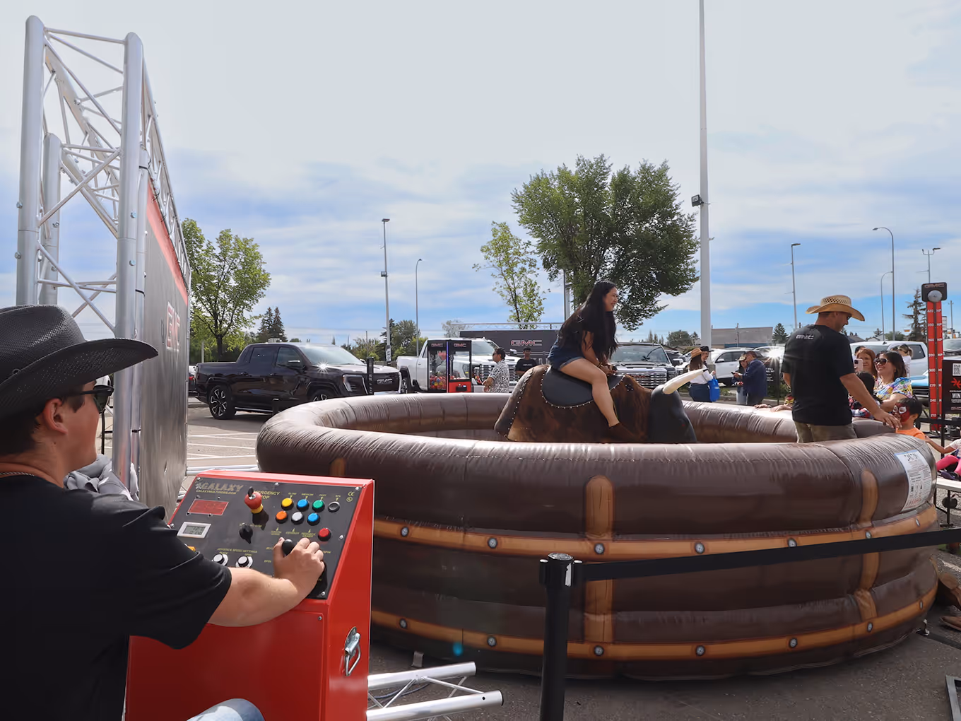 Mechanical bull attraction running at a GMC pop-up event, with operator and spectators nearby.