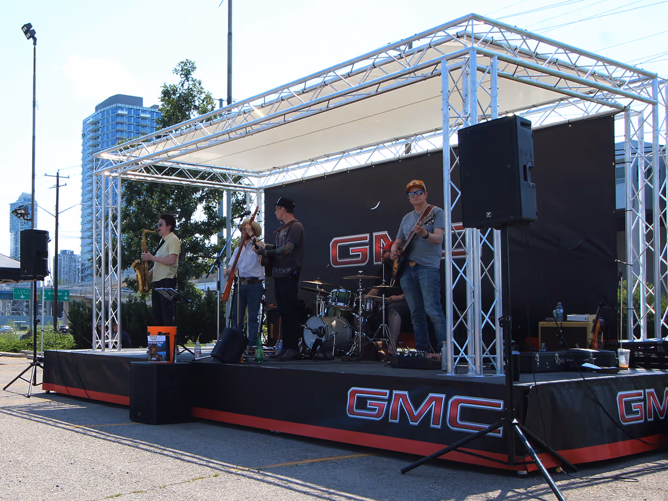Musicians perform on a GMC outdoor rental stage setup during a community Stampede activation.