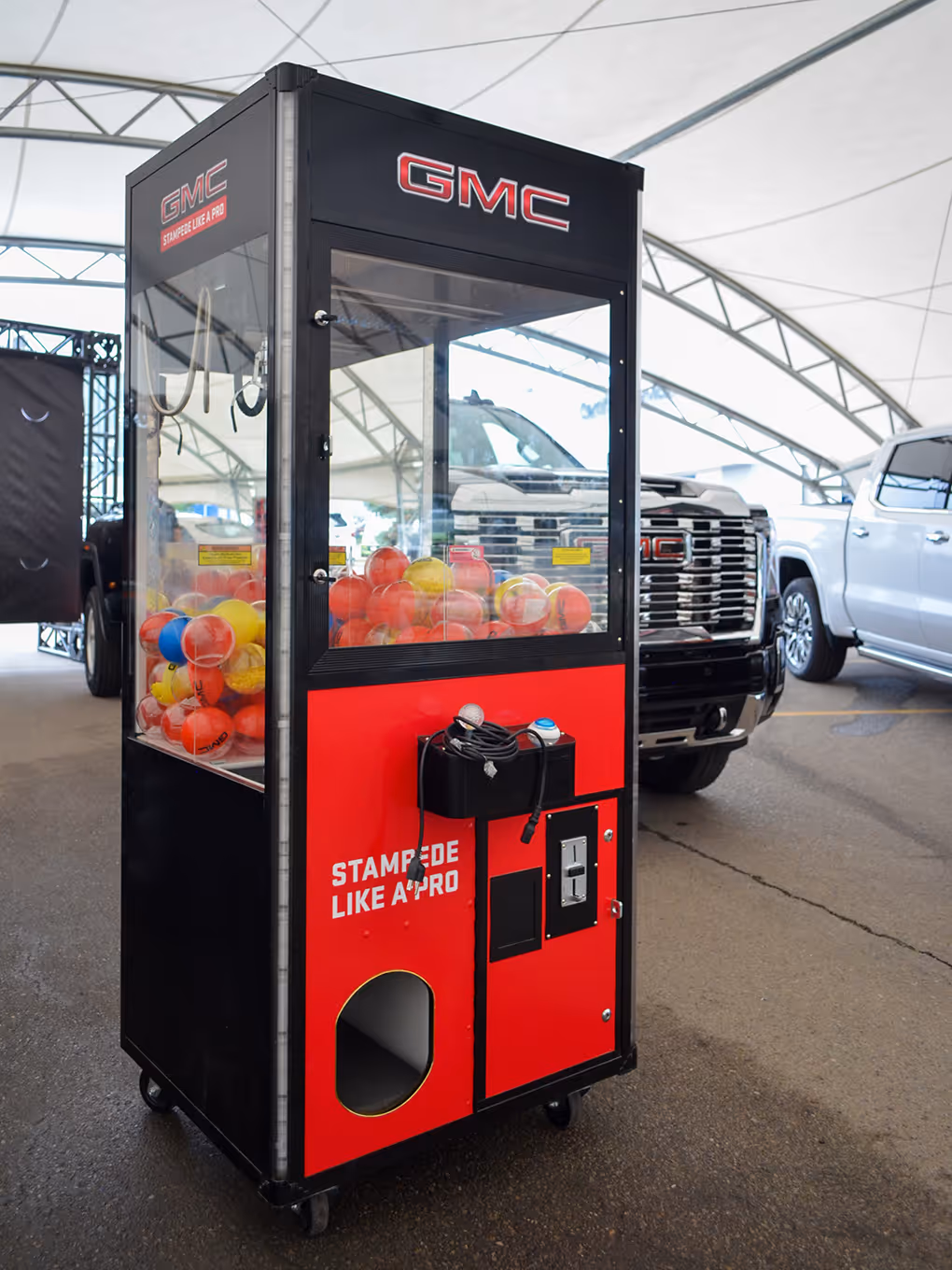 rental Custom GMC claw machine filled with branded prize balls at a Stampede pop-up dealership event.