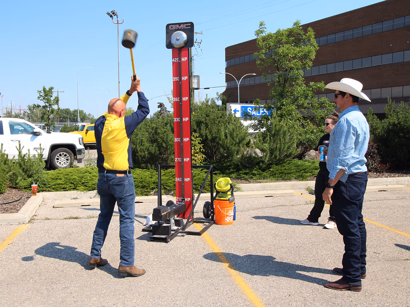 Guest swings a mallet at the rental GMC strength tester game during a community Stampede activation.