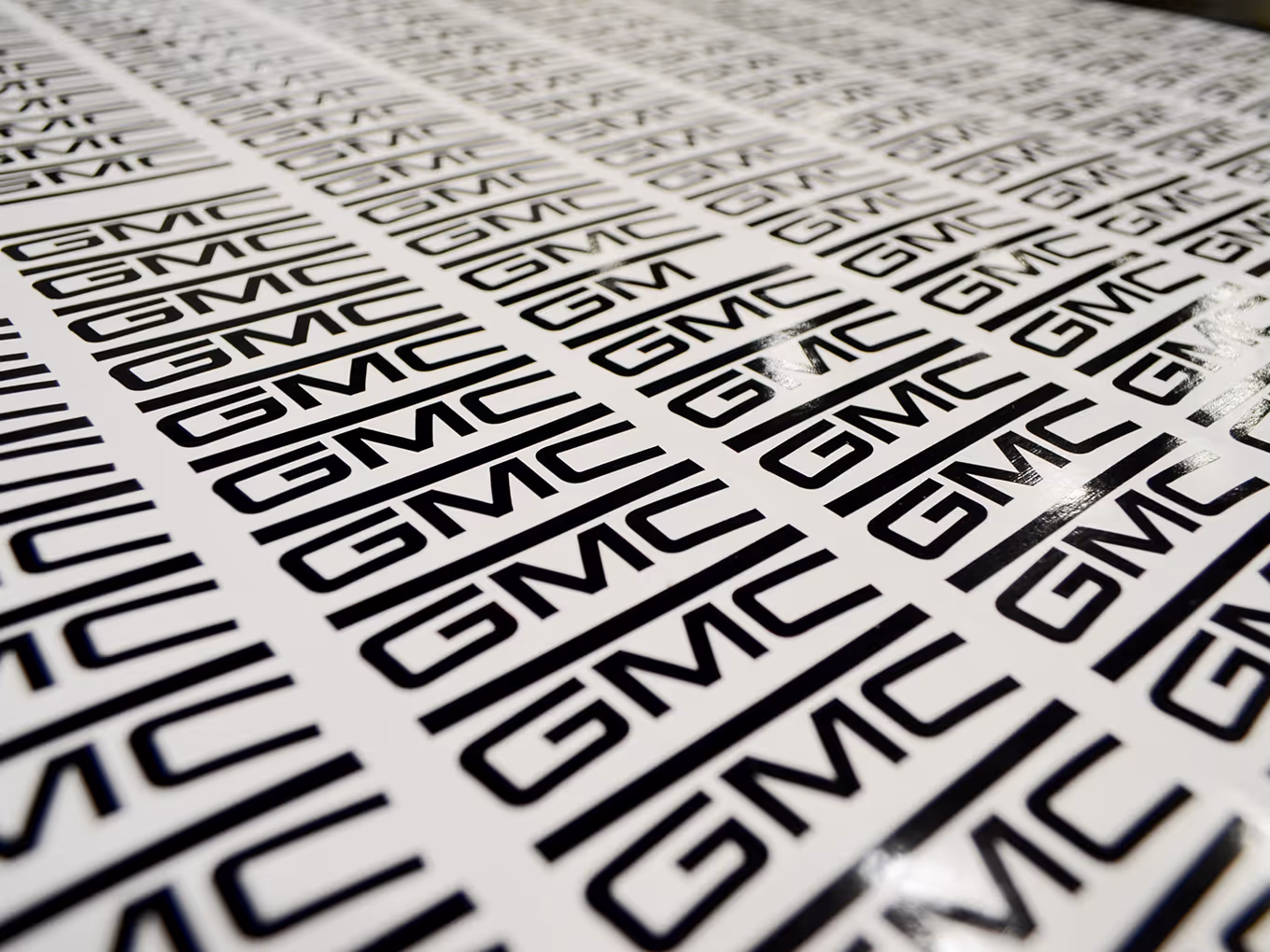 Large sheet of custom printed black GMC logo stickers prepared for branded event elements.