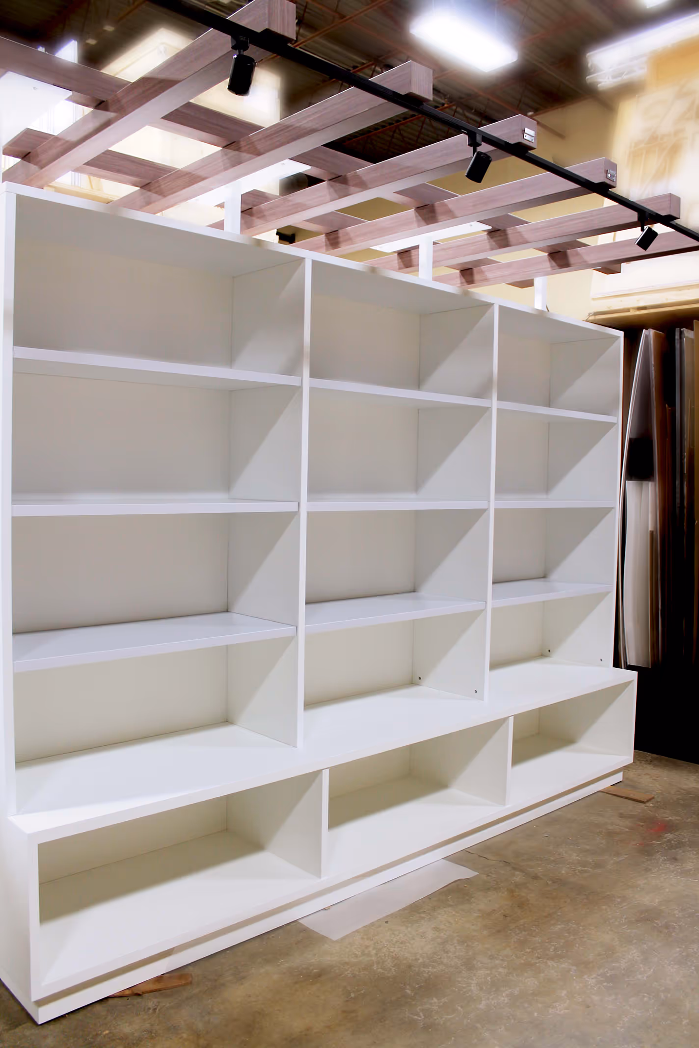 White MDF shelving unit with integrated mini pergola top, built for Indaba’s trade show booth product displays.