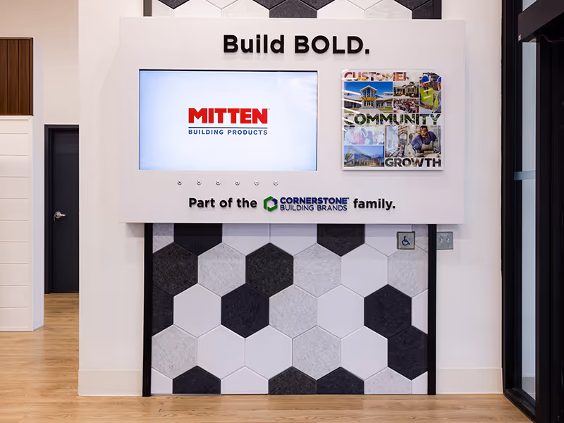 Mitten showroom feature wall with touchscreen display, brand messaging, and hexagon acoustic felt panels in black, white, and gray.