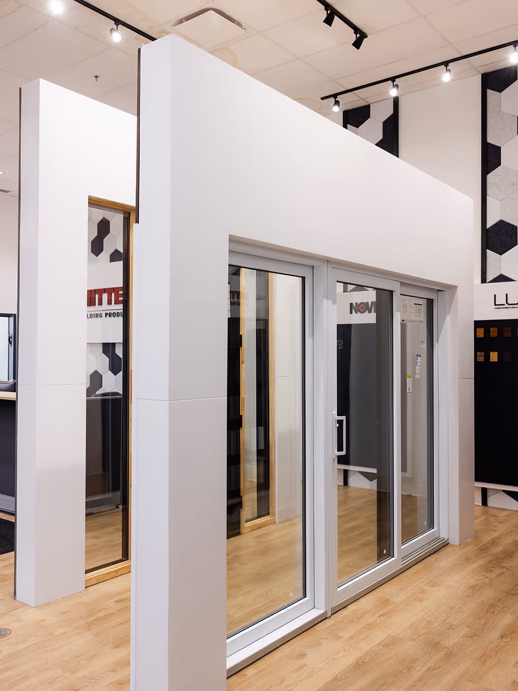 Sliding patio door showcase displayed within a clean white modular showroom structure on wood flooring