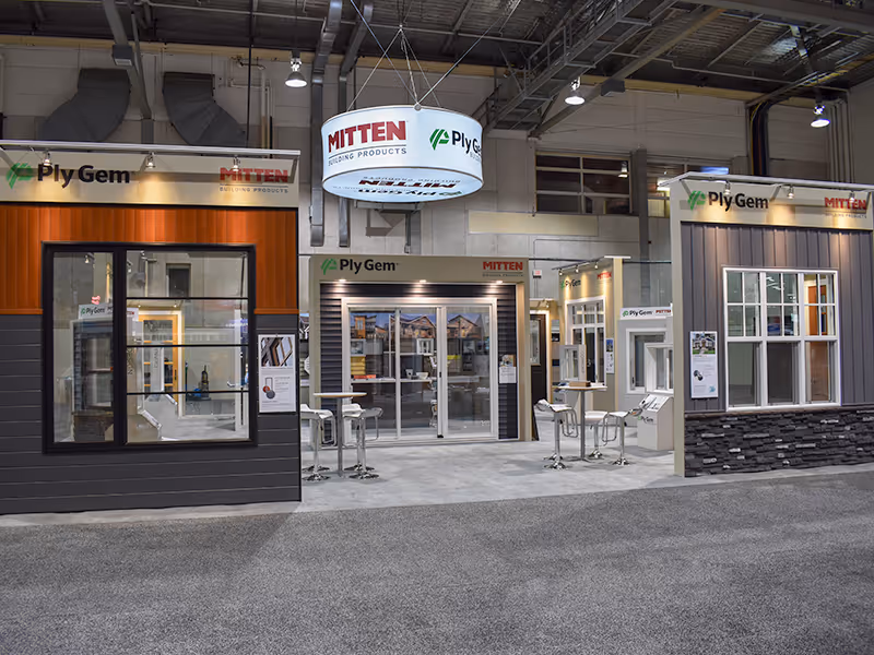 Ply Gem and Mitten exhibit showcasing full-size window displays, textured siding panels, and a stone-style exterior base in a custom-built trade show environment.