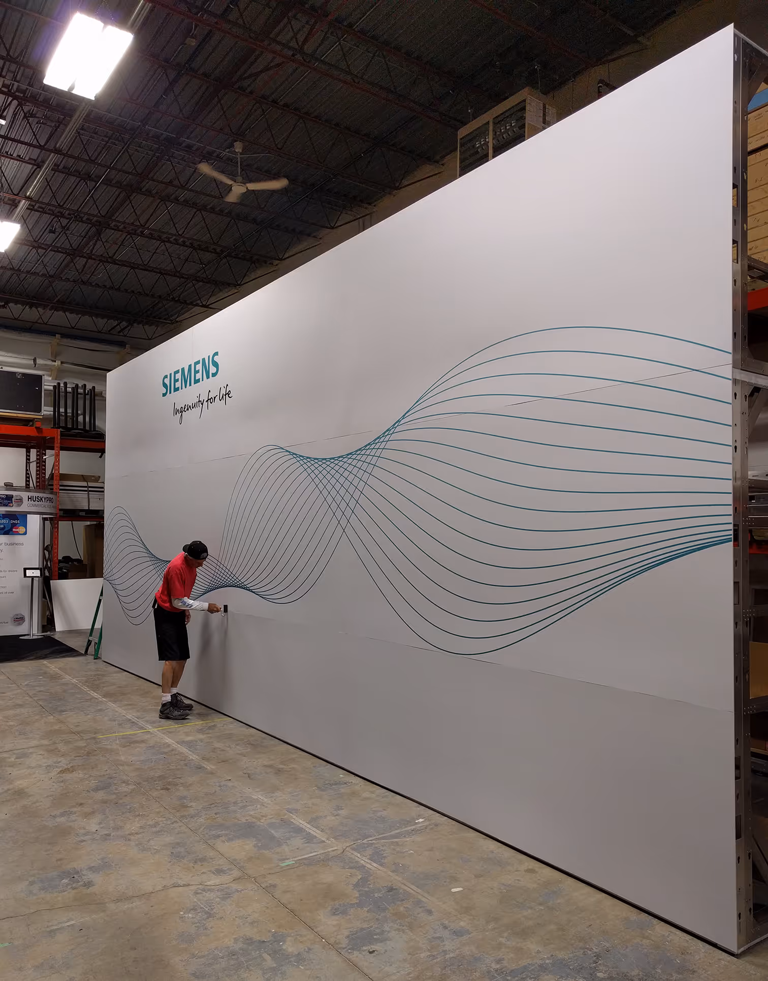 Large Siemens custom fabric backdrop installation with printed wave-line graphics being assembled in the Exhibit Studio production shop.