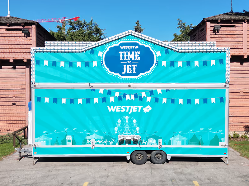 Front-facing image of the WestJet “Time to Jet” carnival trailer with refreshed teal graphics for the Calgary Stampede midway.