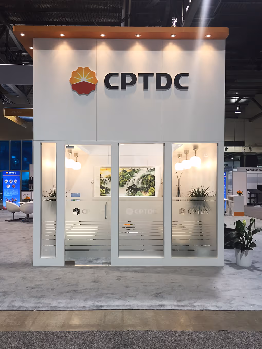 Interior view of the CPTDC private meeting room featuring glass walls, modern white furniture, artwork, and soft lighting.