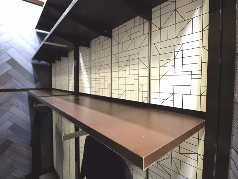 Close-up of Spiritleaf exhibit shelving system with geometric patterned wall panels and custom brown retail shelving.