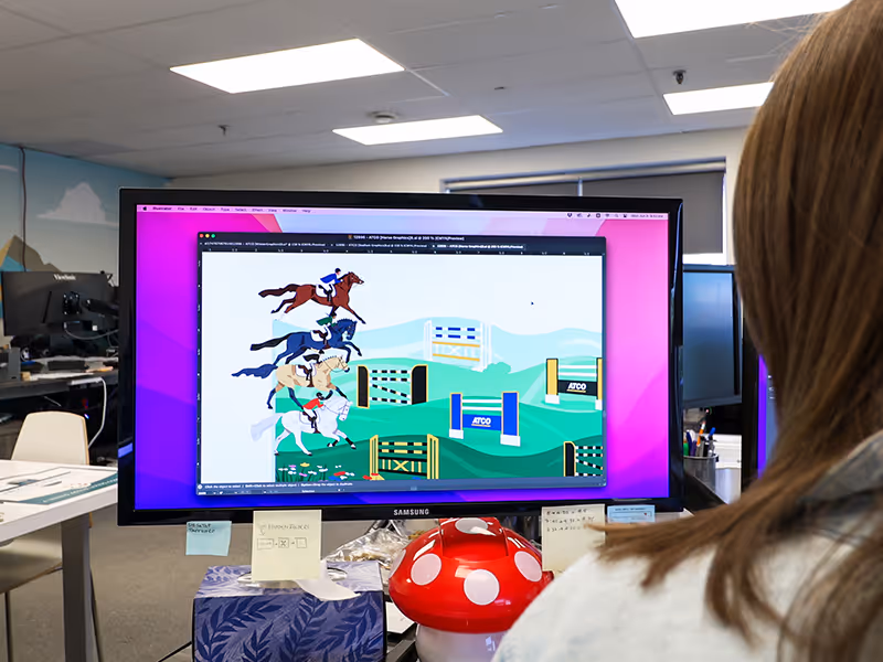 Designer working on ATCO Pedal Prix interactive game graphics in Adobe Illustrator, creating animated horse race visuals for the custom shipping container activation at Spruce Meadows.