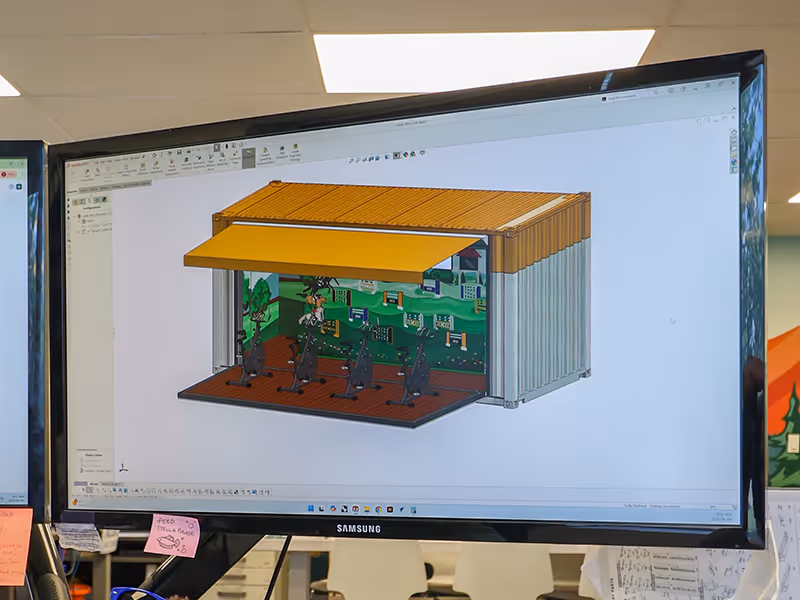 3D rendering of ATCO’s Pedal Prix custom shipping container activation, showing the layout of stationary bikes, race-themed backdrop, and extended awning designed for mobile event use.