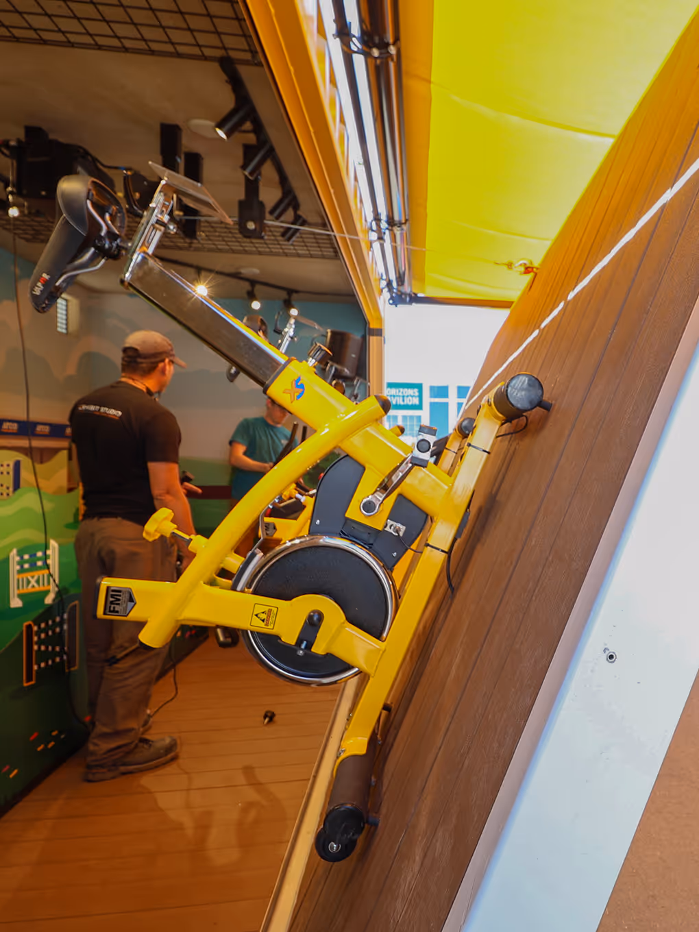 Stationary bike attached to the floor of a partially closed modified shipping container during installation and testing for a brand activation.