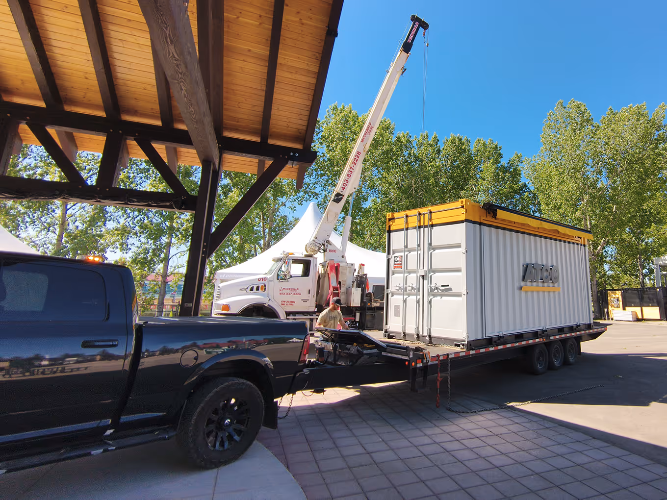 ATCO Pedal Prix custom shipping container activation with crane unloading branded sea can for Spruce Meadows event setup.