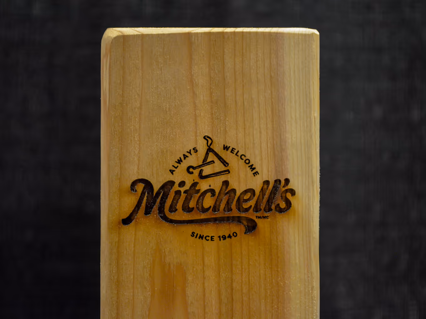Wood-burned Mitchell’s logo engraved on cedar post used for custom dinner bell at the Bacon Battle event.