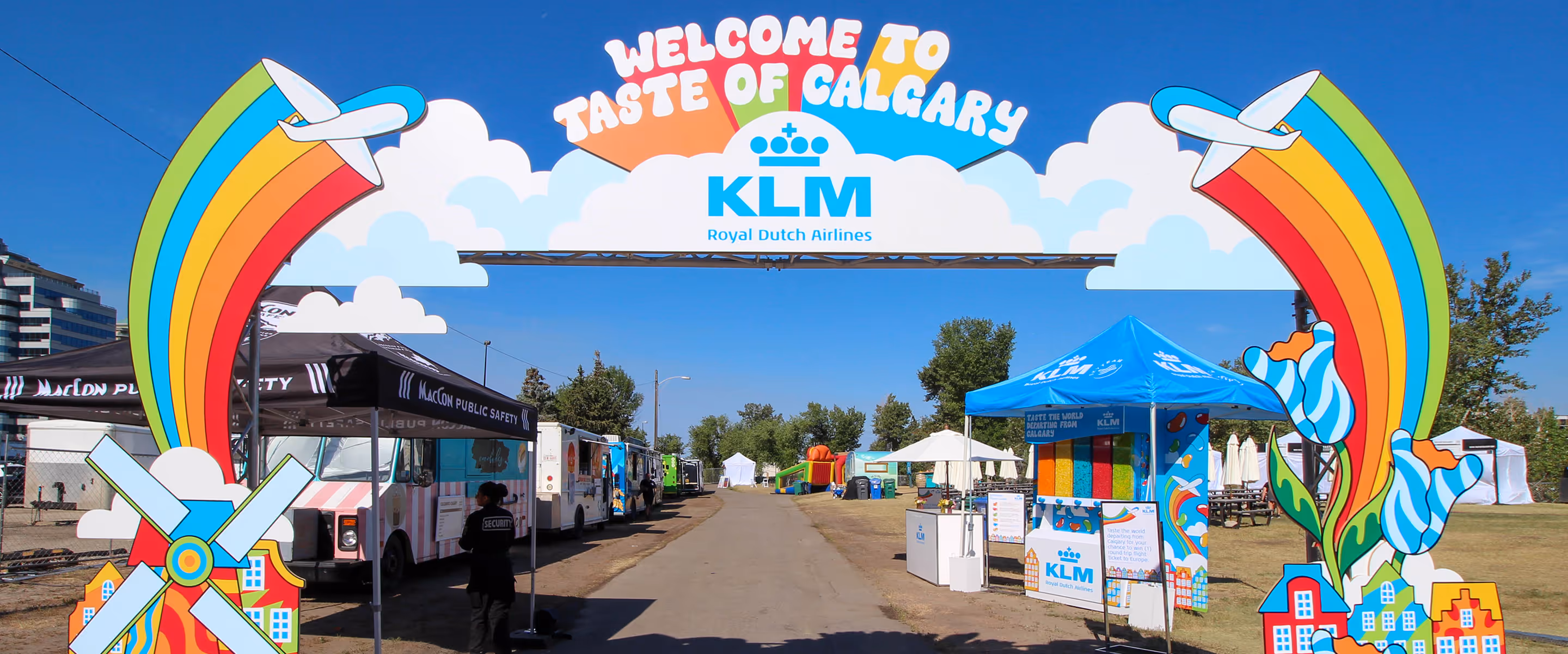 Bright, custom-built KLM festival entry arch at Taste of Calgary featuring colourful rainbows, planes, and Dutch-inspired graphics welcoming visitors.