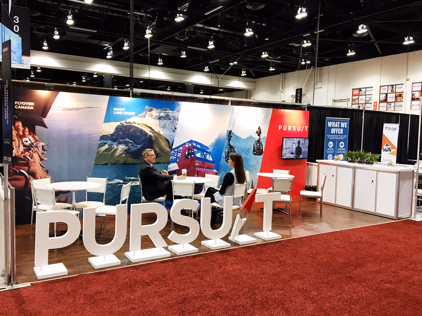 10x20 portable Pursuit trade show booth with scenic fabric backdrop, seating area, and oversized white 3D “PURSUIT” letters.