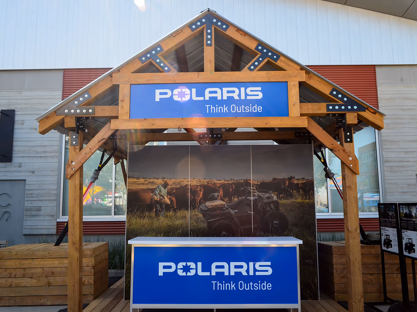 Polaris branded wooden booth with custom structural framing, roof beams, and vinyl backdrop showcasing off-road vehicles in a rugged outdoor display.