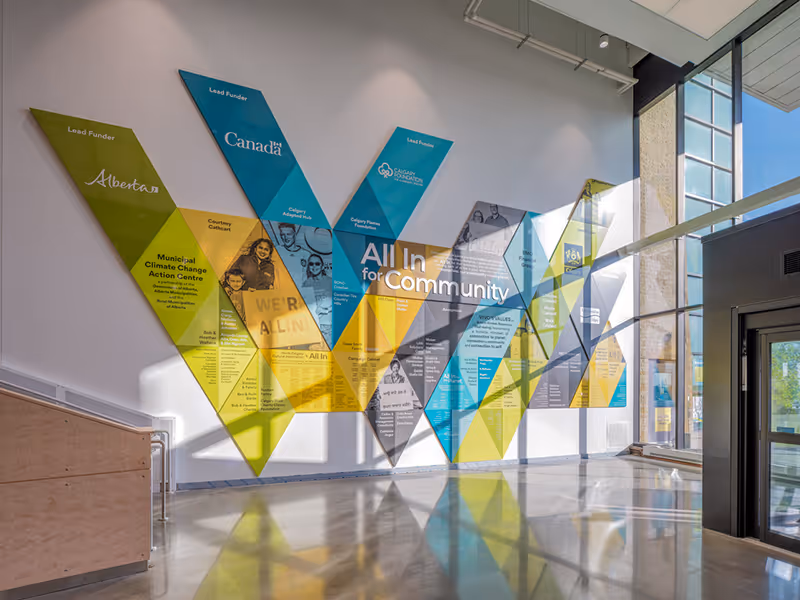 Angled view of Vivo’s All In For Community recognition wall with vibrant geometric panels honouring donors, staff, and volunteers.
