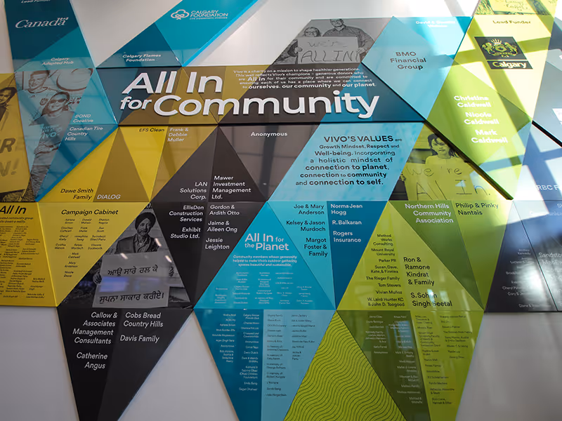 Bright, full-height geometric donor wall at Vivo with layered ACM panels, anti-graffiti laminate, and acrylic lettering in a high-traffic public space.