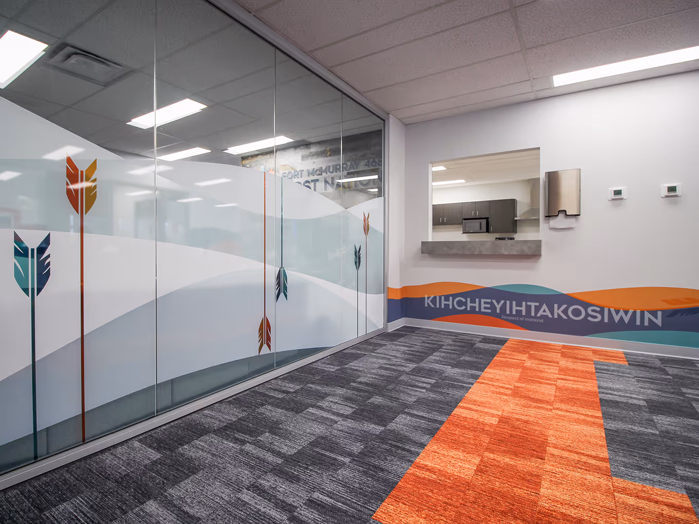 Office interior featuring privacy film with arrow graphics and wall vinyl displaying Cree value “Kihcheyihtakosiwin.”