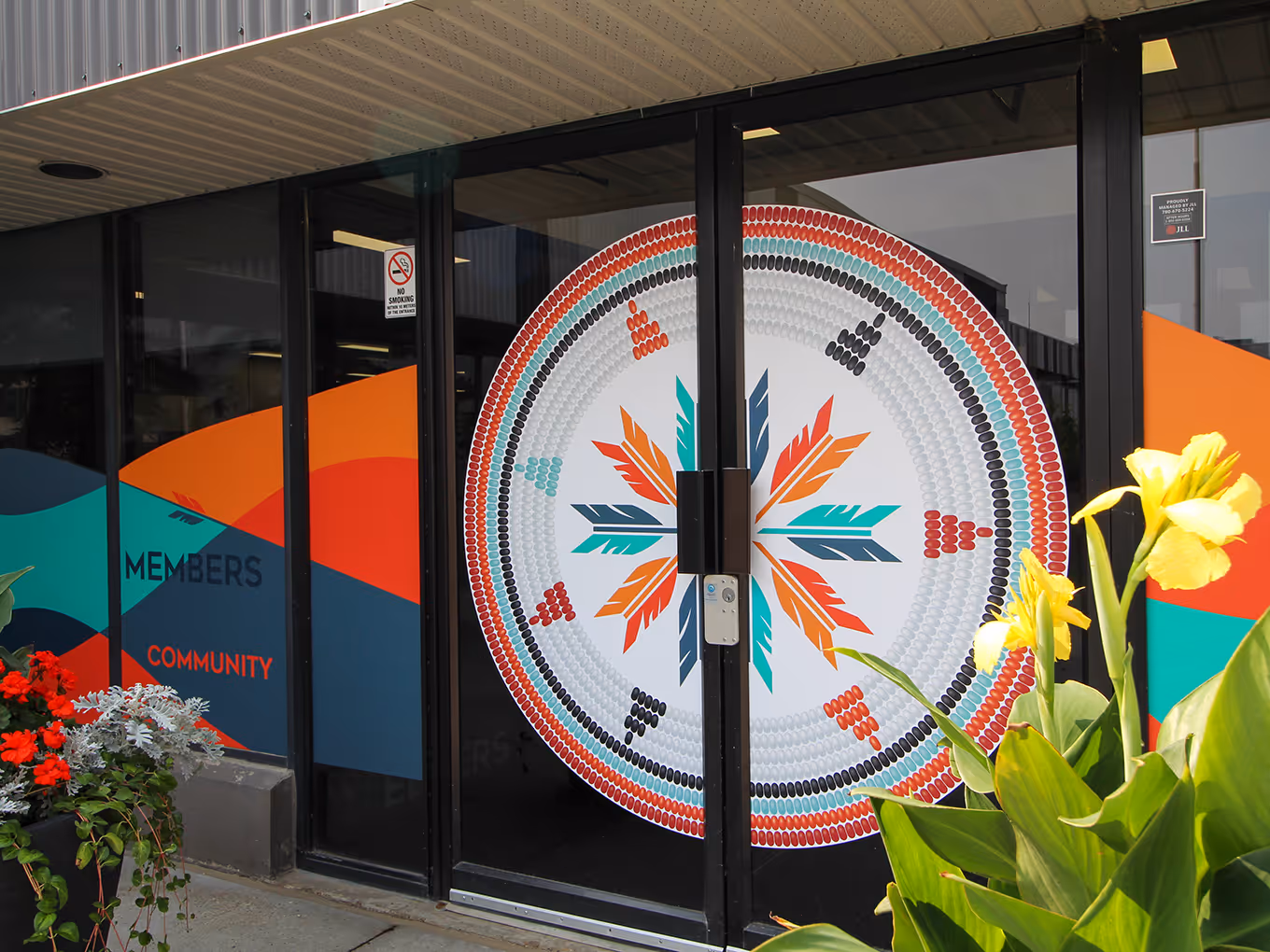 Full-colour exterior window vinyl featuring circular beadwork-inspired feather design at the Fort McMurray 468 First Nation office entrance.