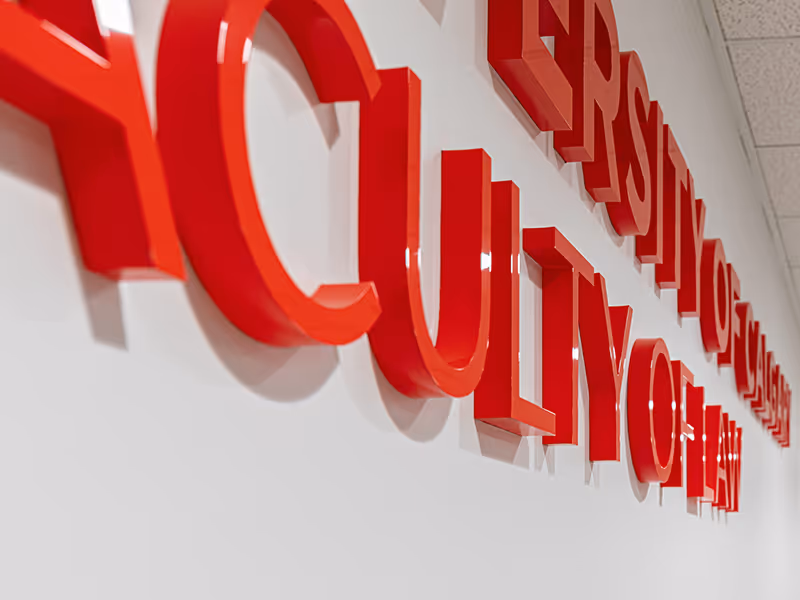 Dimensional University of Calgary Faculty of Law lettering mounted on a white interior wall.