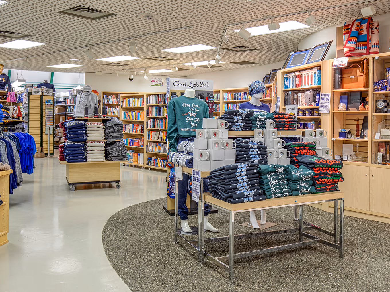 Central merchandise tables and apparel displays within the University of Lethbridge Bookstore interior.