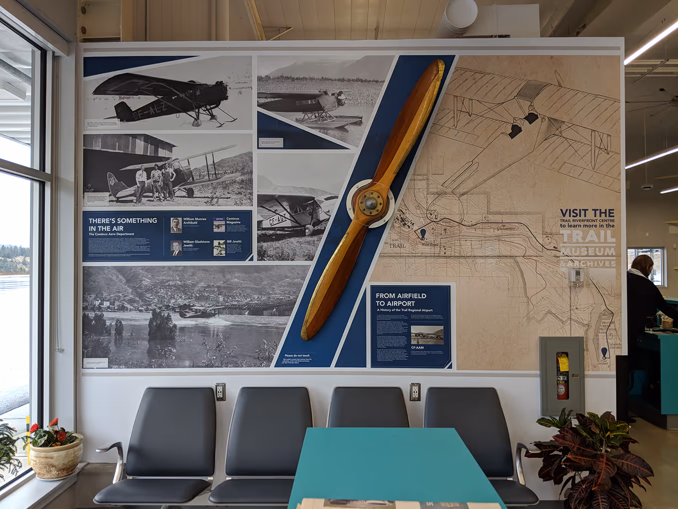 Aviation history exhibit at Trail Regional Airport featuring archival photographs, interpretive panels, and a mounted aircraft propeller.