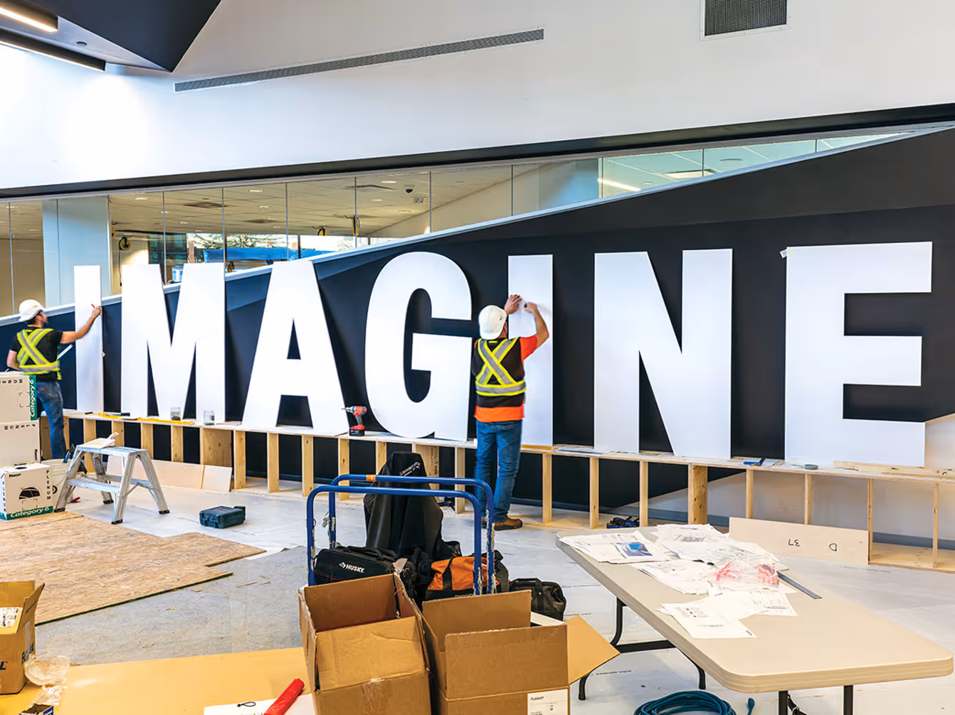  Installation in progress of the Imagine donor recognition wall at the Stanley A. Milner Library, featuring oversized lettering and custom construction.