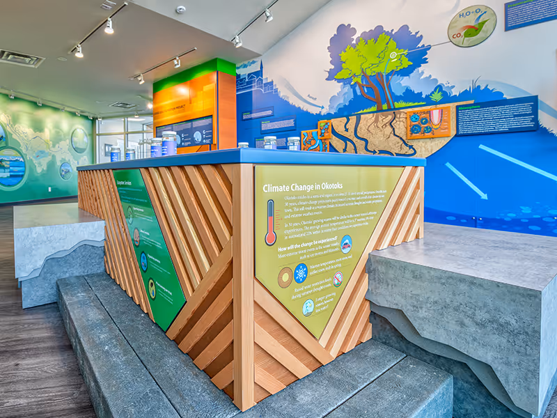 Visitors engaging with a hands-on soil and water filtration exhibit designed to teach sustainability concepts at the Town of Okotoks Interpretive Centre.