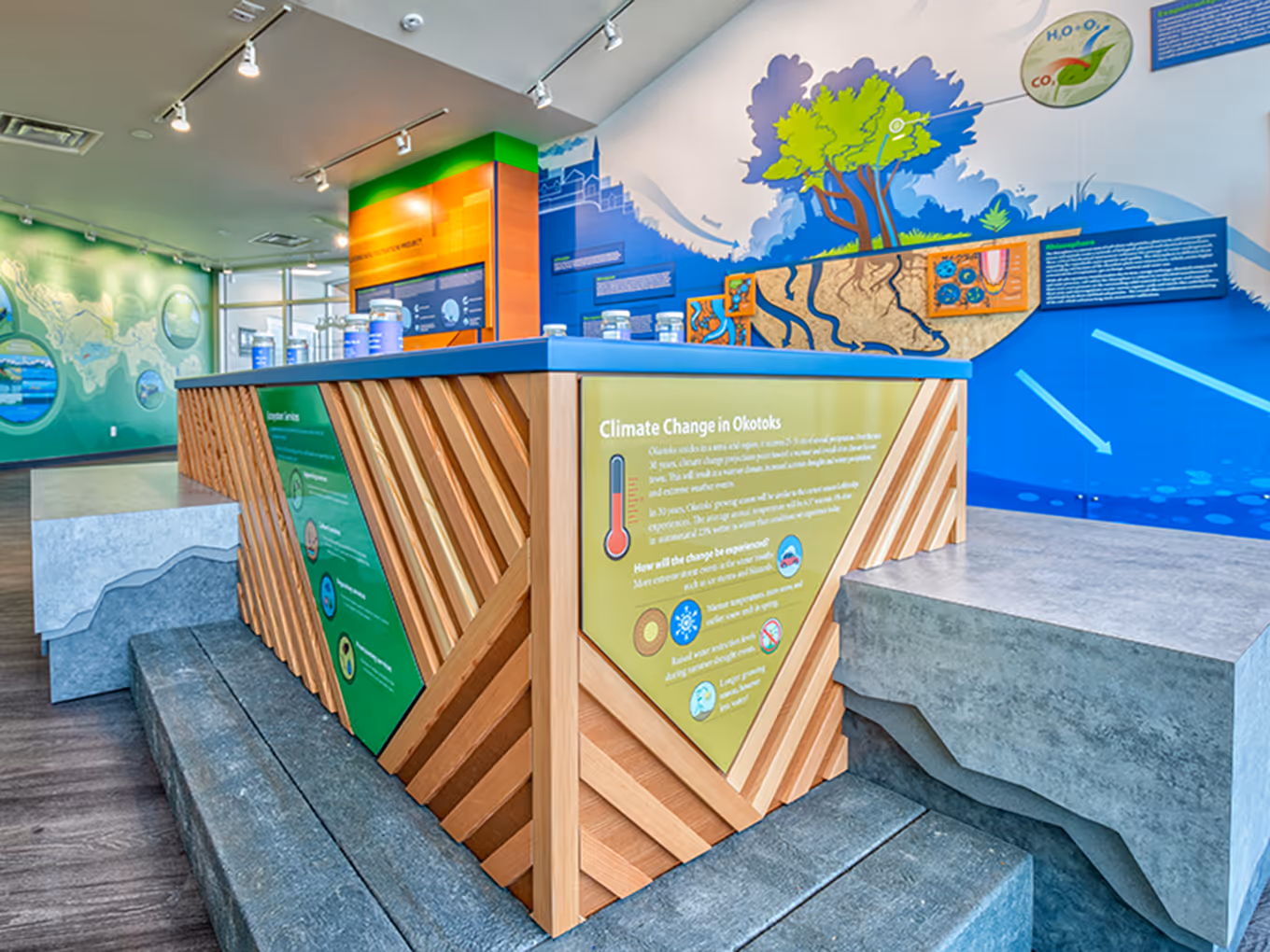 Interior view of the Town of Okotoks Interpretive Centre showcasing integrated wall murals, interactive displays, and an open learning environment.