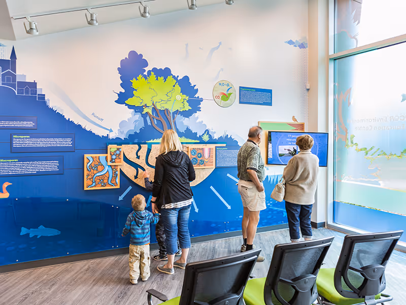 Exterior entry area of the Town of Okotoks Interpretive Centre featuring interpretive graphics that connect indoor exhibits to the surrounding landscape.