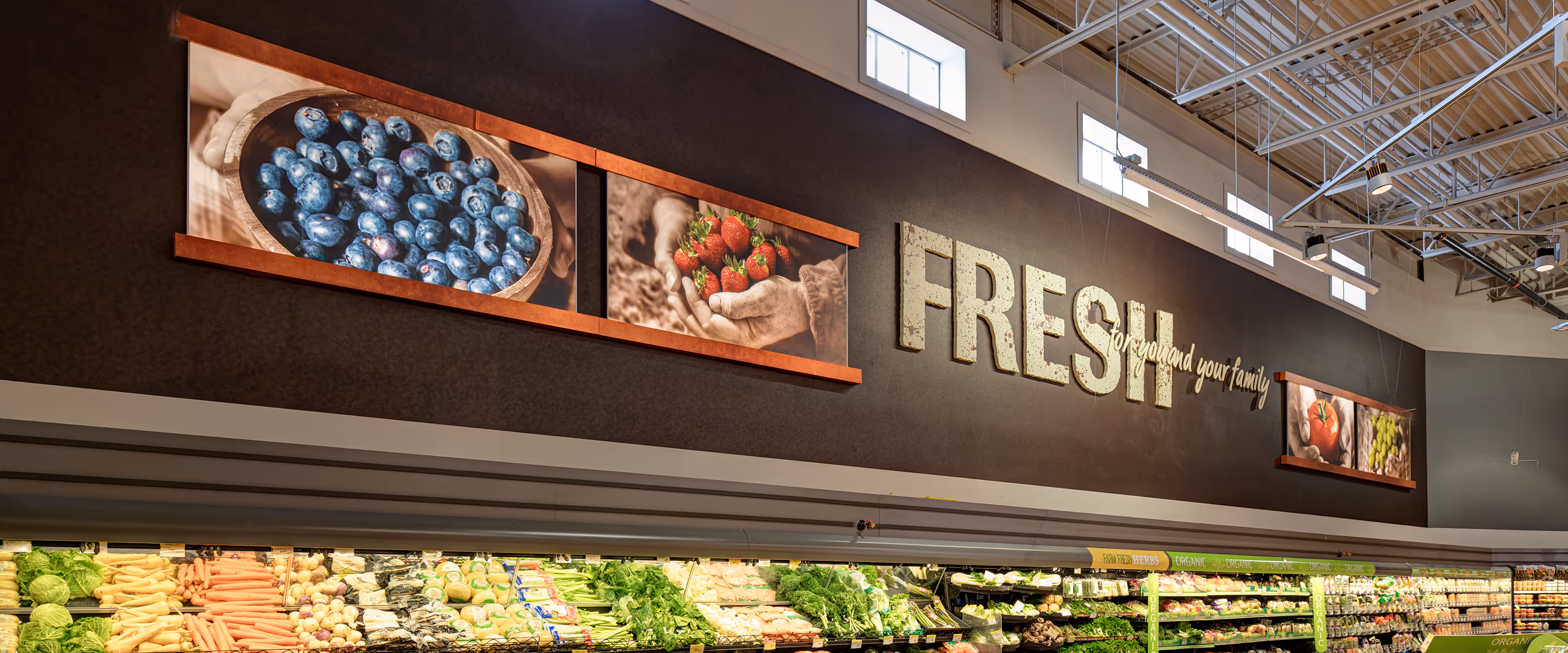 Wide view of the Calgary Co-op produce department featuring custom illuminated LED panels and large-format lifestyle imagery above refrigerated displays.