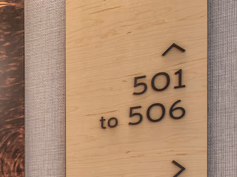 Detail view of dimensional room numbers mounted on a wood wayfinding panel for clear guest navigation.