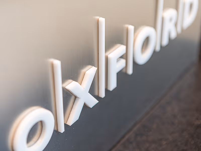Oxford Properties LEED award display combining brushed aluminum, frosted glass awards, and dimensional white acrylic logo.