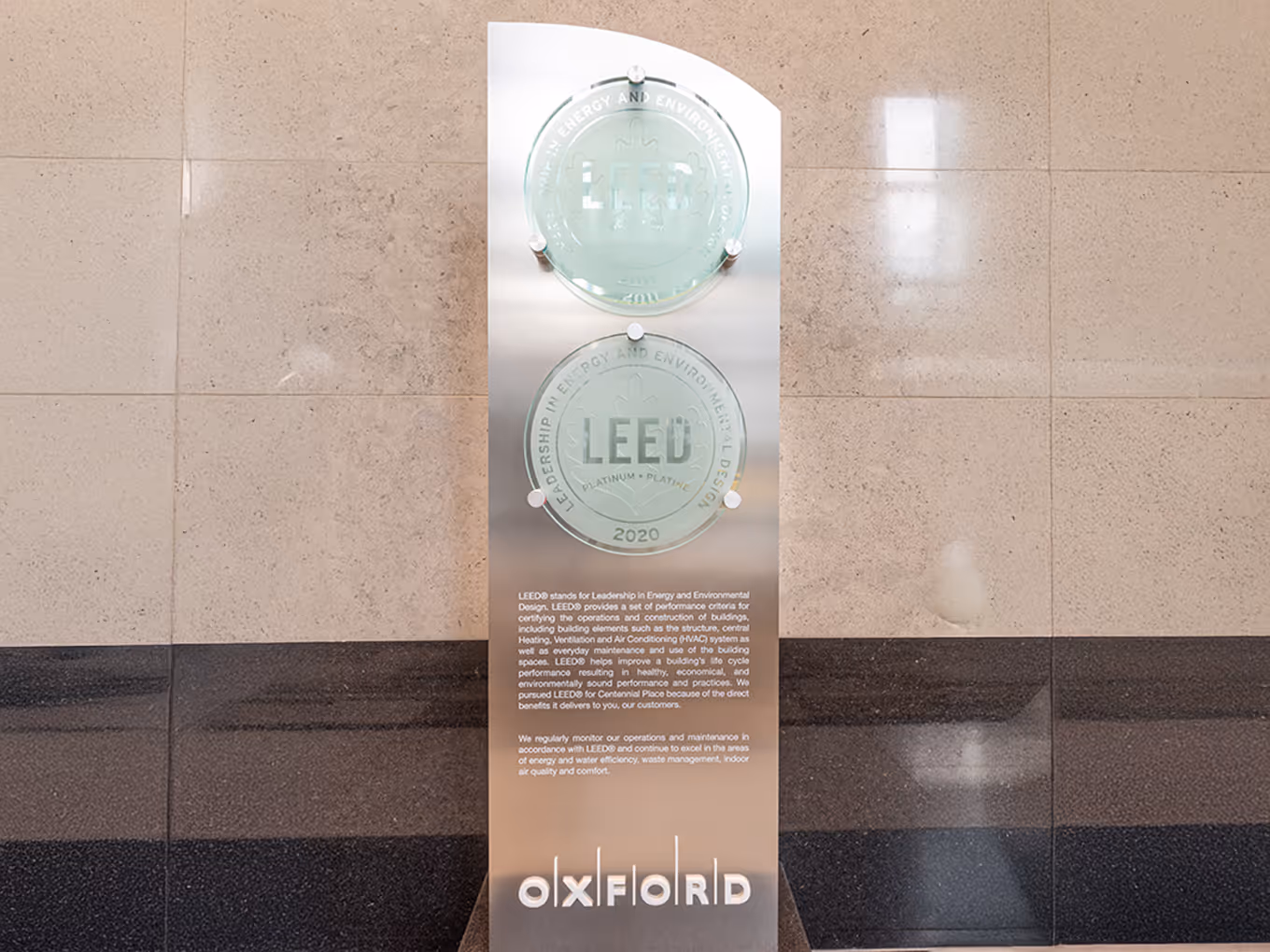 Full-height freestanding LEED award display showcasing sustainability achievements at Centennial Place in downtown Calgary.